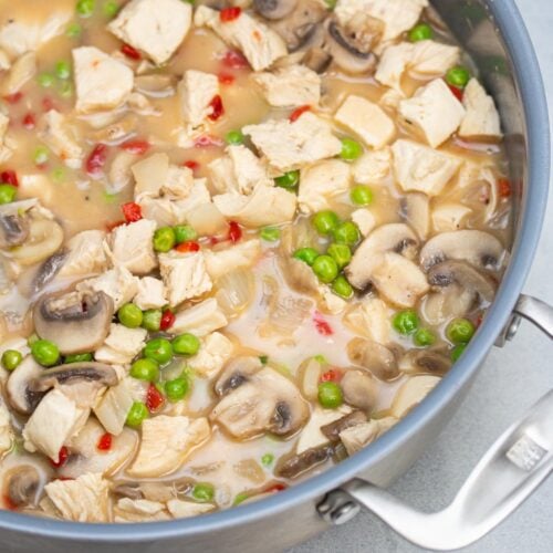 Chicken and veggies simmering in a saucepan.