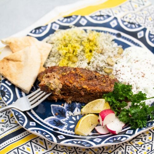 Plate with Persian meatloaf with rice and accompaniments.