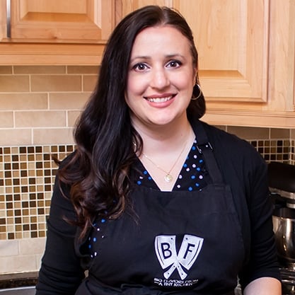Ashley Covelli standing in the kitchen wearing an apron with the Big Flavors logo.