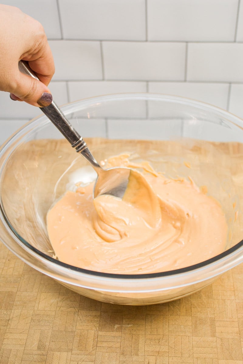 Stirring together peanut butter and butterscotch chips in a mixing bowl.