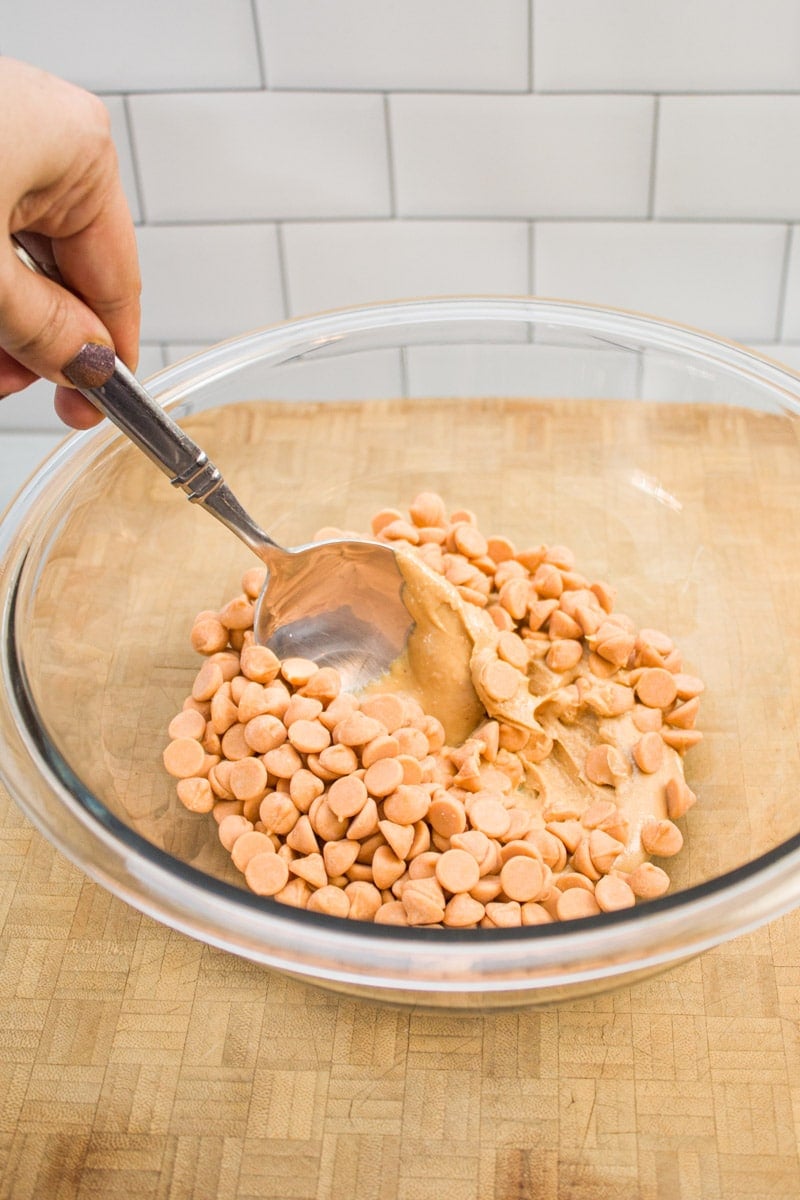 Stirring together peanut butter and butterscotch chips in a mixing bowl.