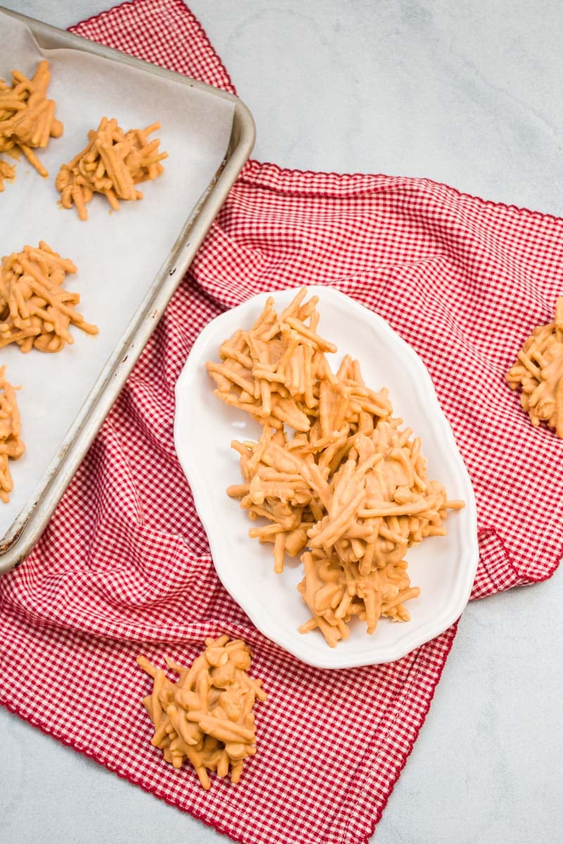 Butterscotch haystacks laid out on a platter with a sheet pan alongside.