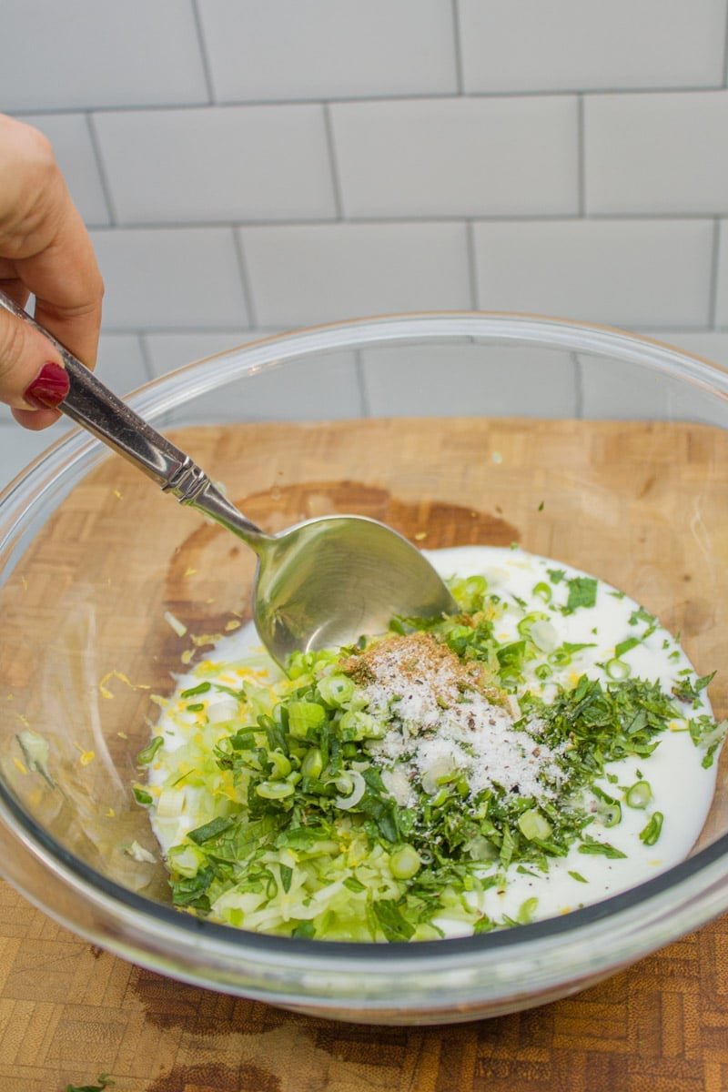 Stirring together a bowl of ingredients for cucumber raita.