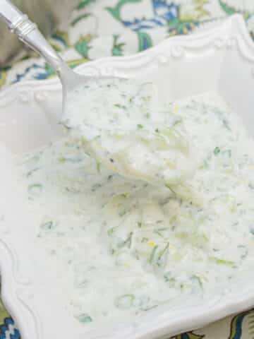 Spoonful of cucumber raita in a bowl.