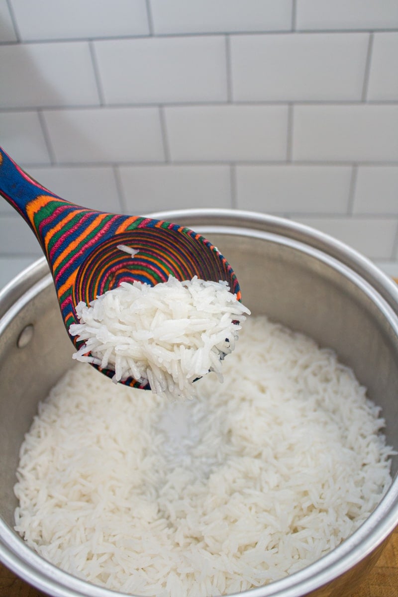 Lifting a spoonful of par-cooked rice from a 