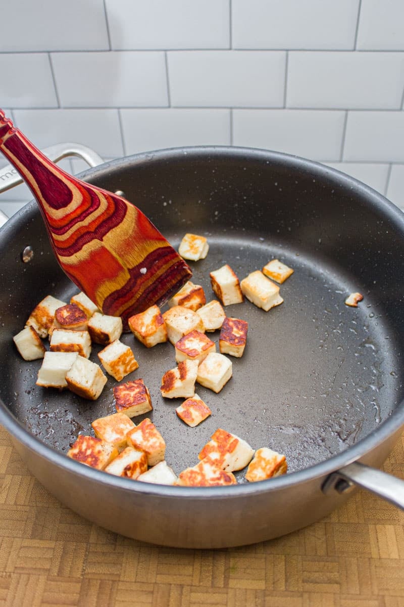 Sautéing cubes of paneer cheese in a skillet.