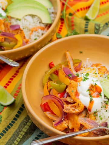 Chicken fajita bowls with rice, avocados, and garnishes.