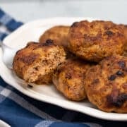 Platter of homemade breakfast sausage patties with one cut in half.