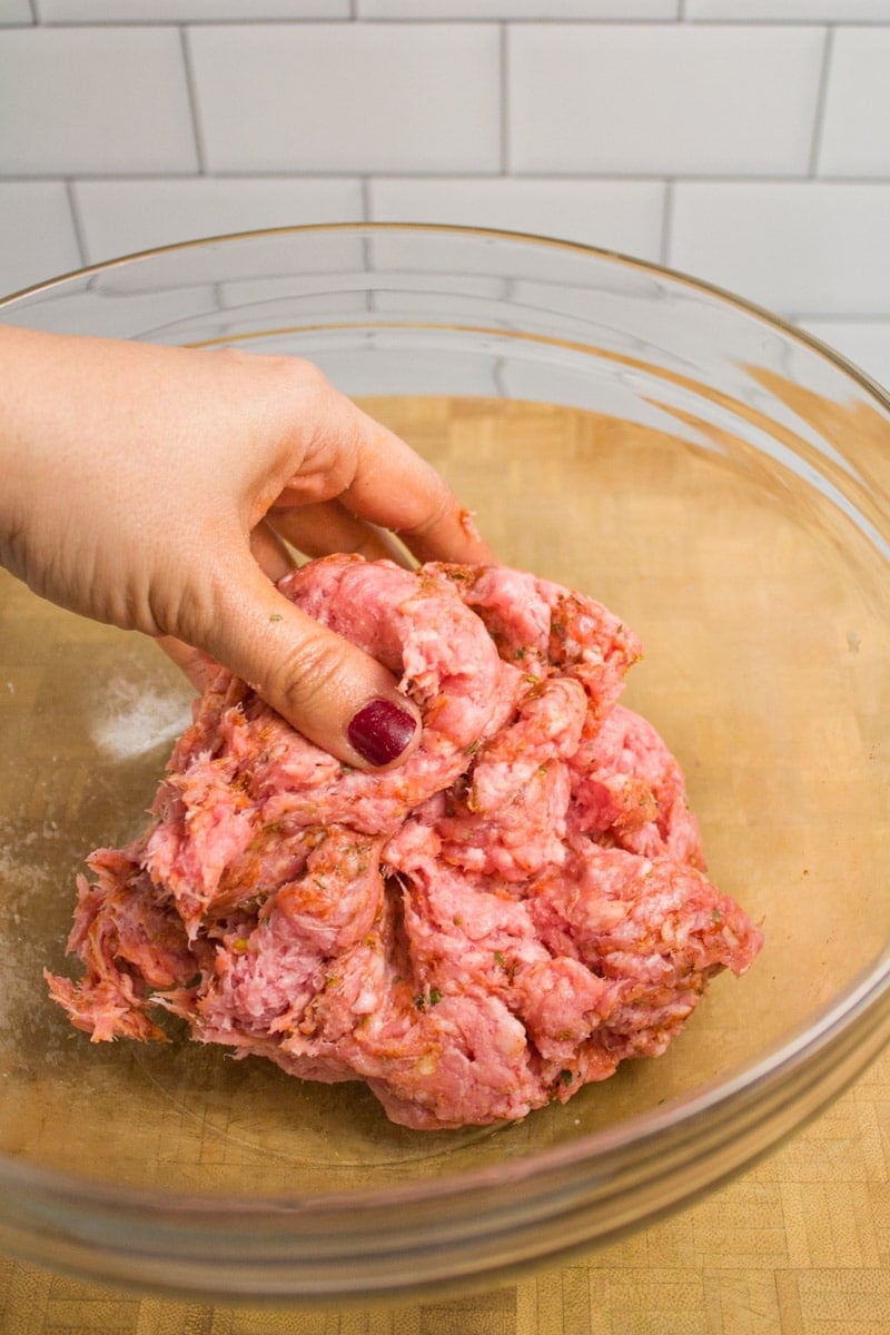 Mixing together a bowl of ground pork and spices to make breakfast sausage patties.