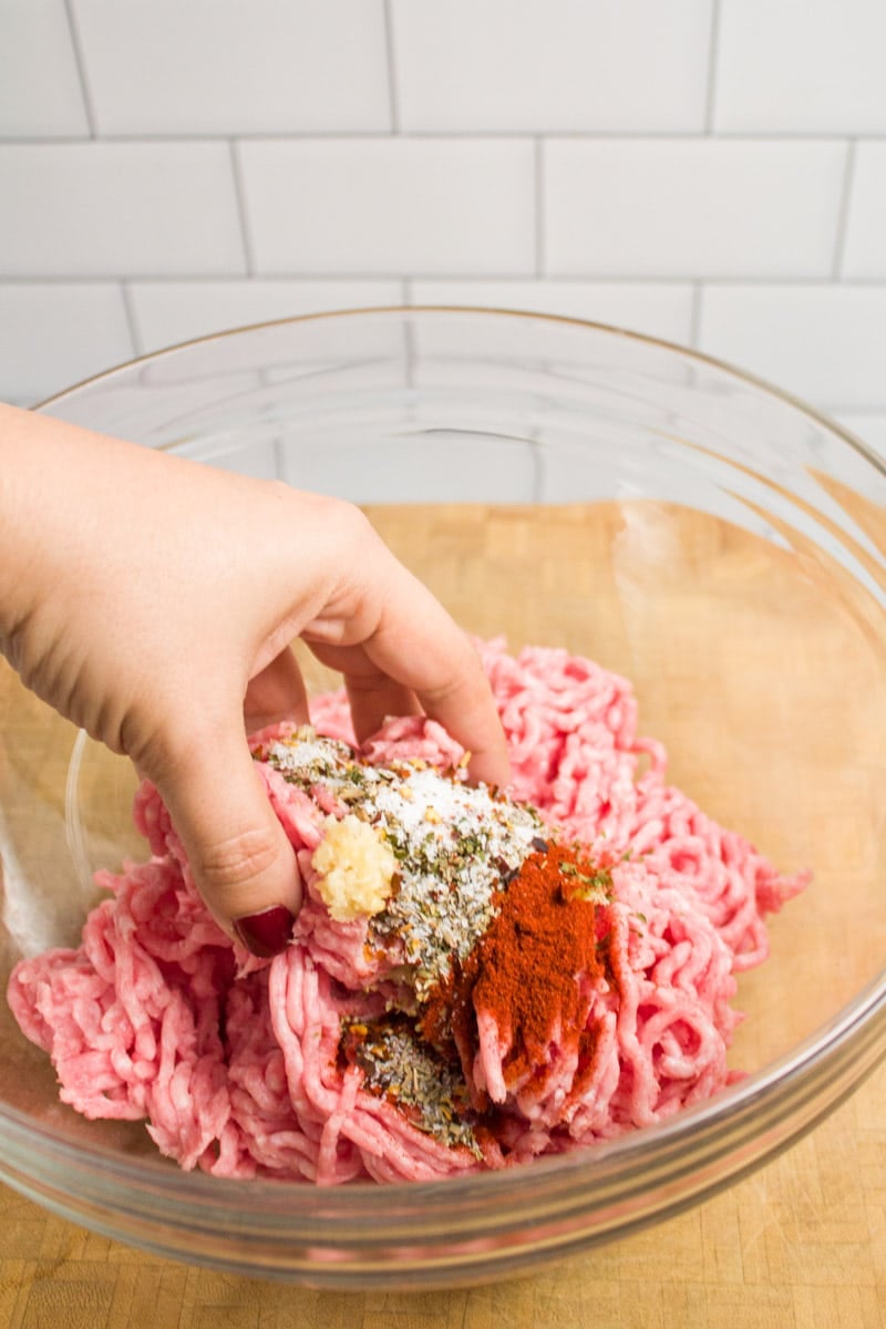 Mixing together a bowl of ground pork and spices to make breakfast sausage patties.