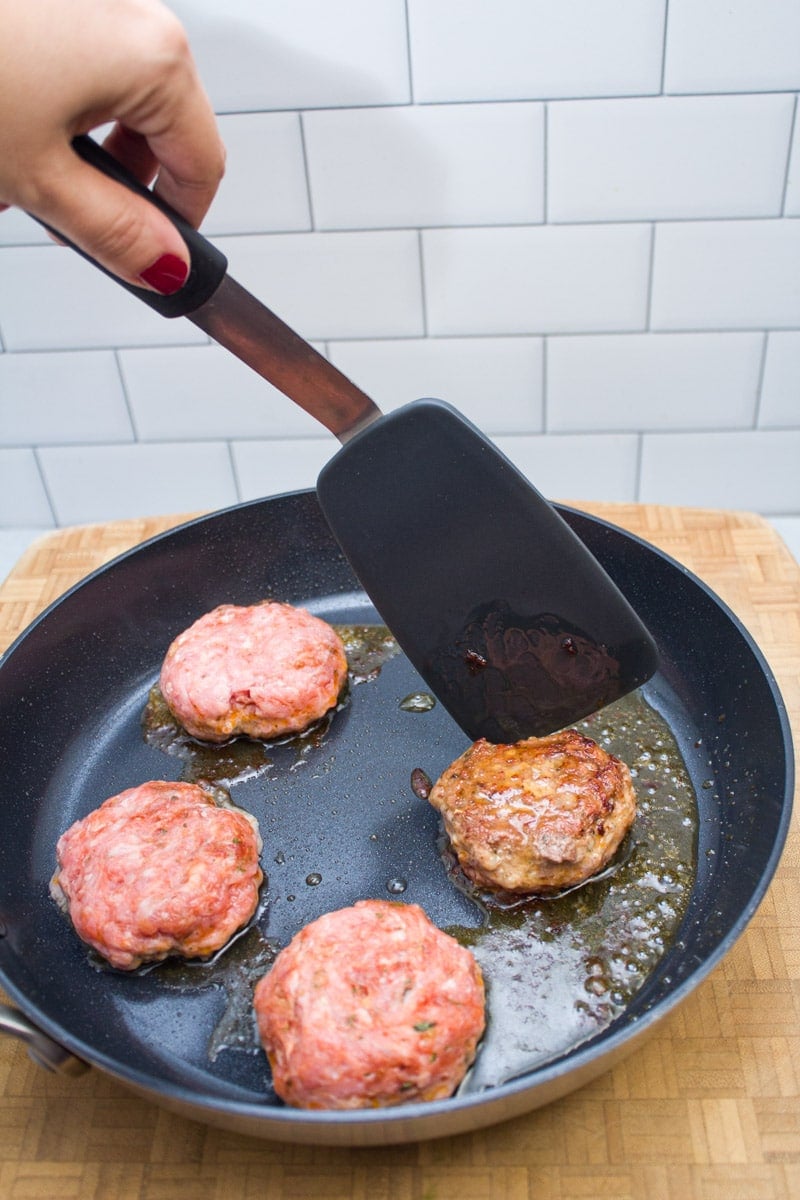 Flipping breakfast sausage patties in a skillet.