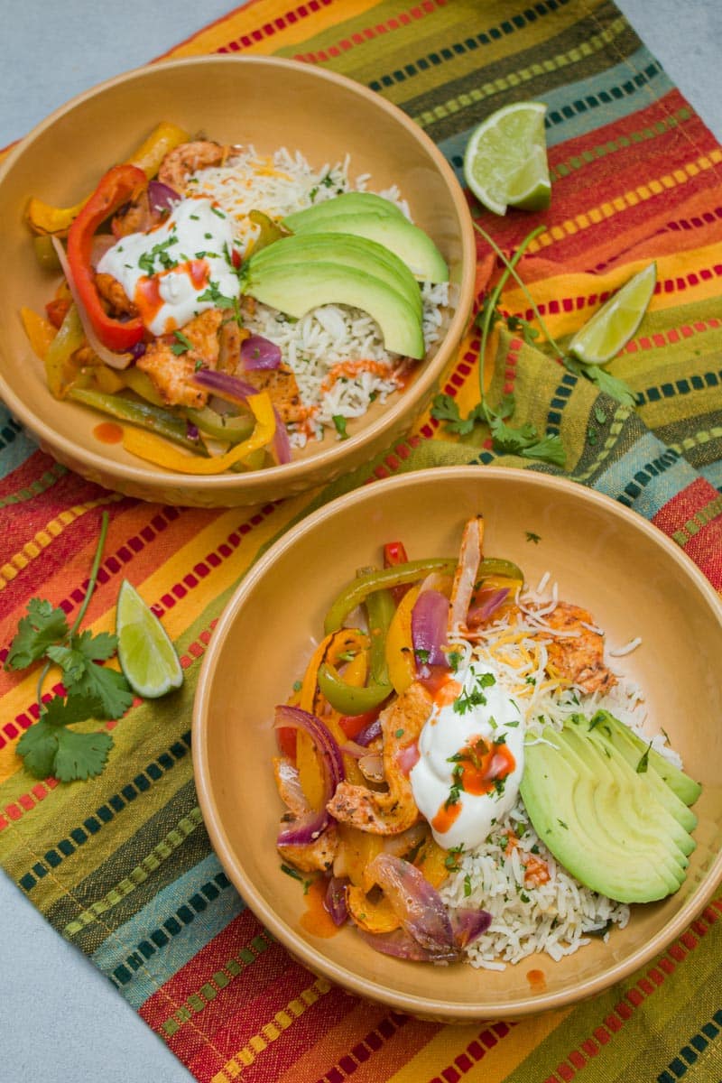 Chicken fajita bowls with cilantro rice, shredded cheese, sliced avocado, Greek yogurt, and hot sauce.