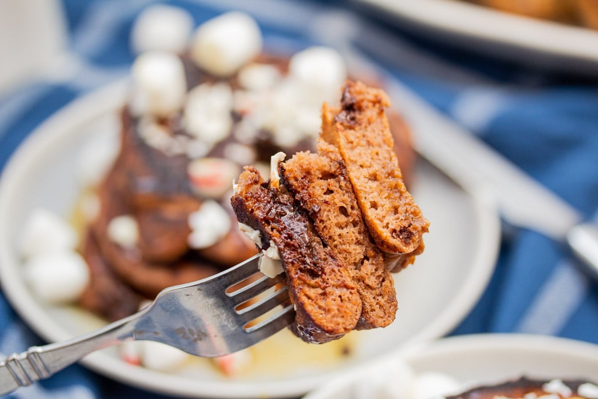 Fork holding 3 layers of sliced chocolate chocolate chip pancakes.