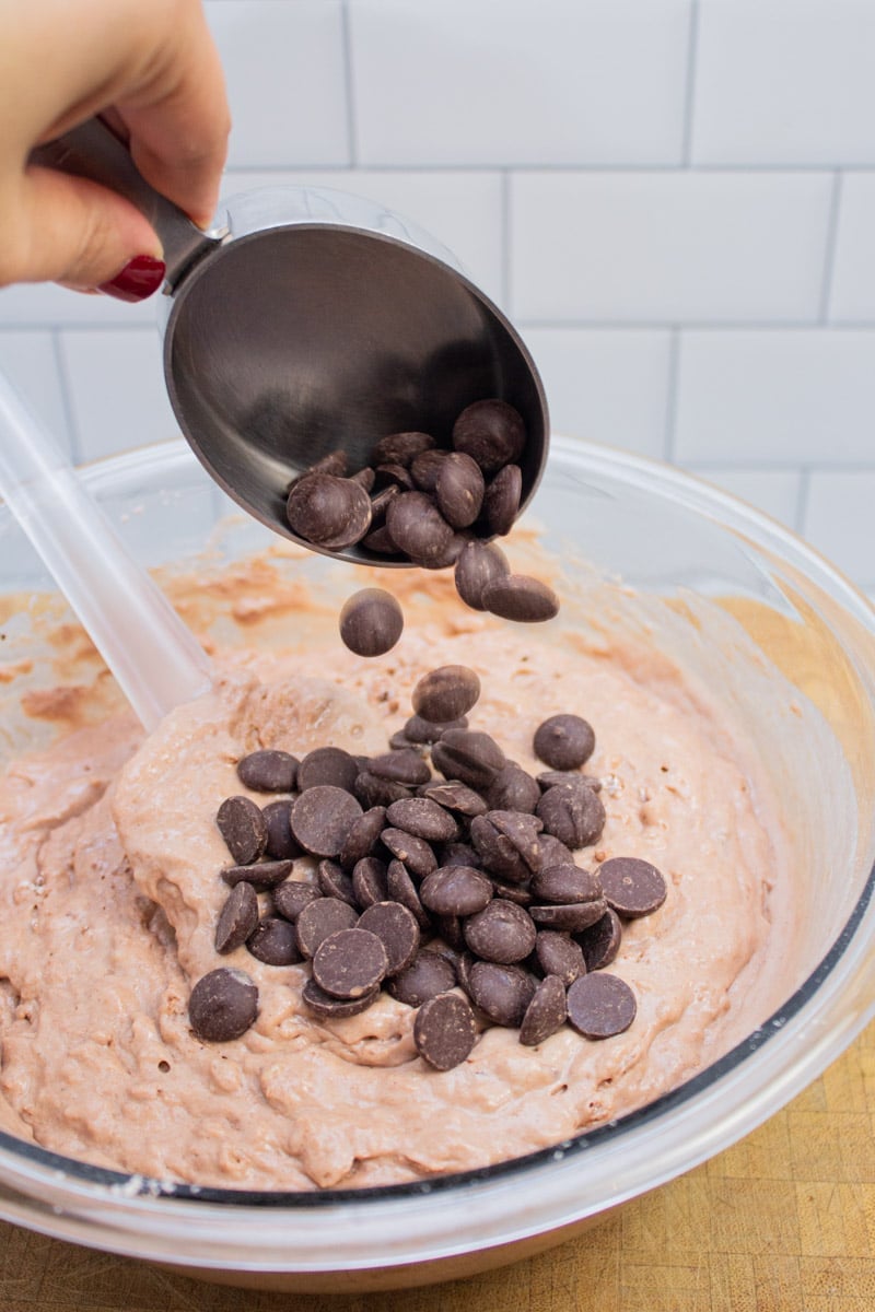 Adding chocolate chips to a chocolate pancake batter.