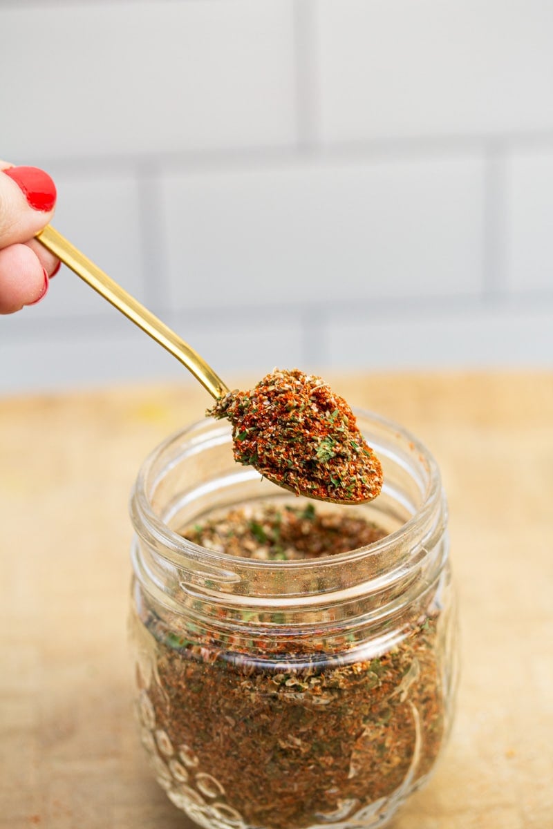 Scooping a spoonful of breakfast sausage seasoning from a jar.