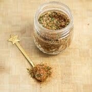 A jar of breakfast sausage seasoning with a spoonful of the mix scooped out.