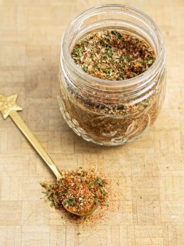 A jar of breakfast sausage seasoning with a spoonful of the mix scooped out.