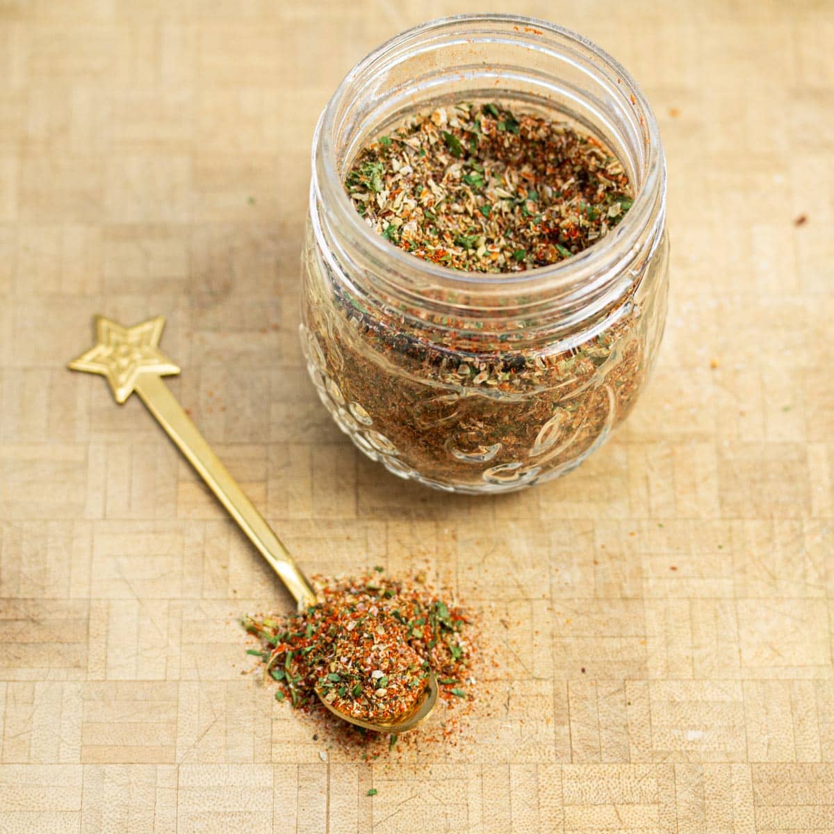 A jar of breakfast sausage seasoning with a spoonful of the mix scooped out.