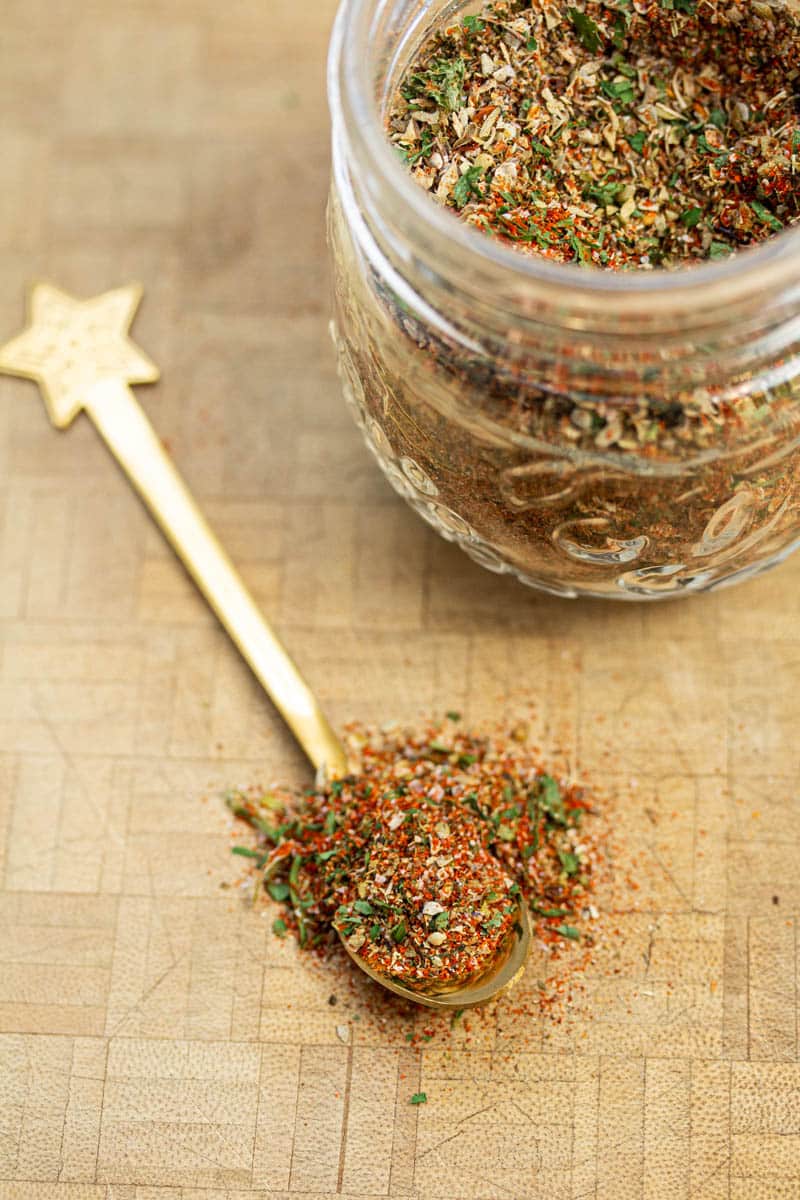 A jar of breakfast sausage seasoning with a spoonful of the mix scooped out.