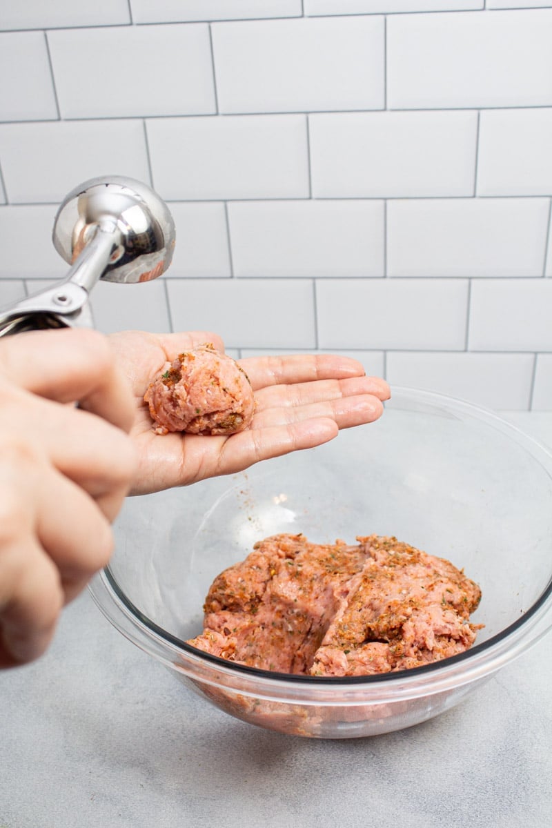 Using a scoop to portion out the meat for turkey sausage patties.