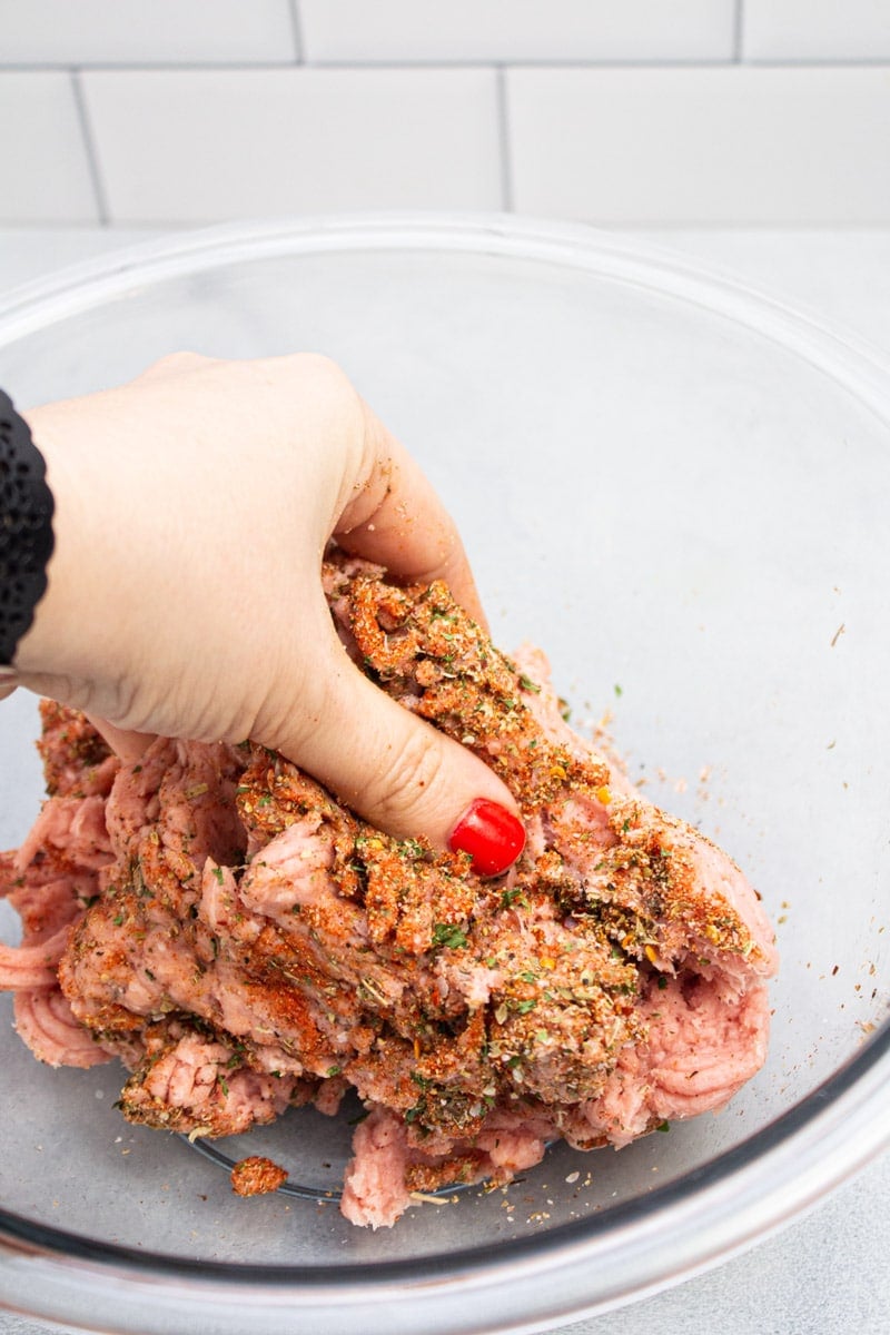 Mixing breakfast sausage spices into ground turkey.