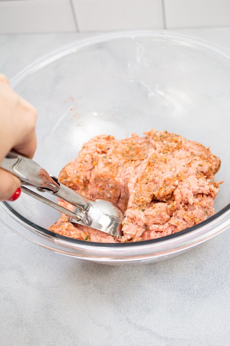 Scooping up seasoned ground turkey to make sausage patties.