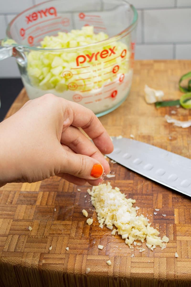 Sprinkling salt over chopped garlic.