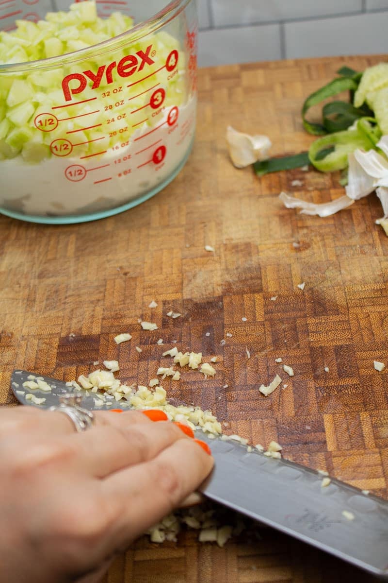 Smashing garlic and salt into a paste with a knife.