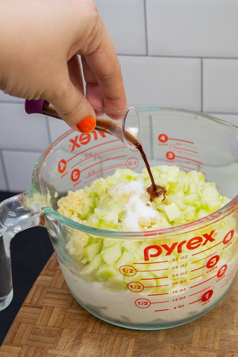 Adding Worcestershire sauce to a bowl of homemade tzatziki.