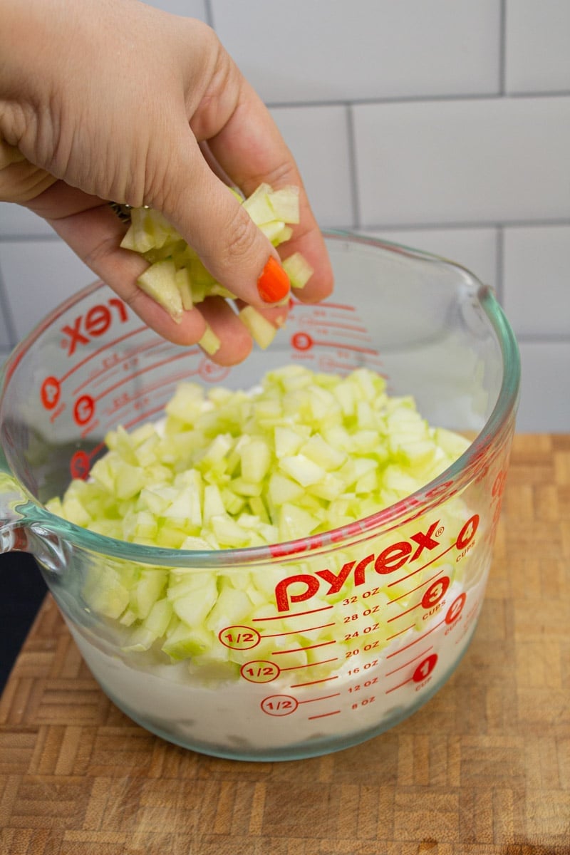 Adding chopped cucumber to Greek yogurt for tzatziki.