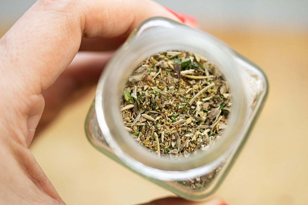 Holding a jar of homemade Italian seasoning blend.