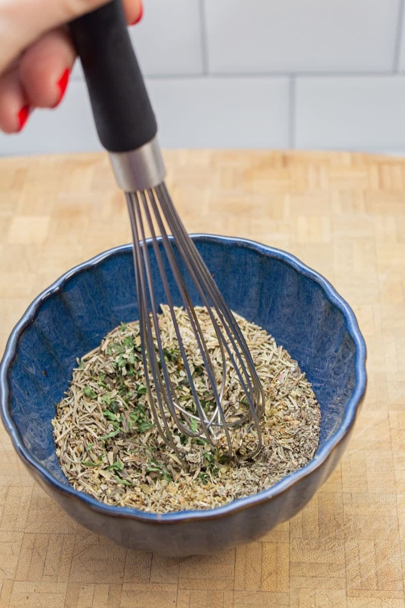 Whisking together ingredients for a homemade Italian seasoning blend.