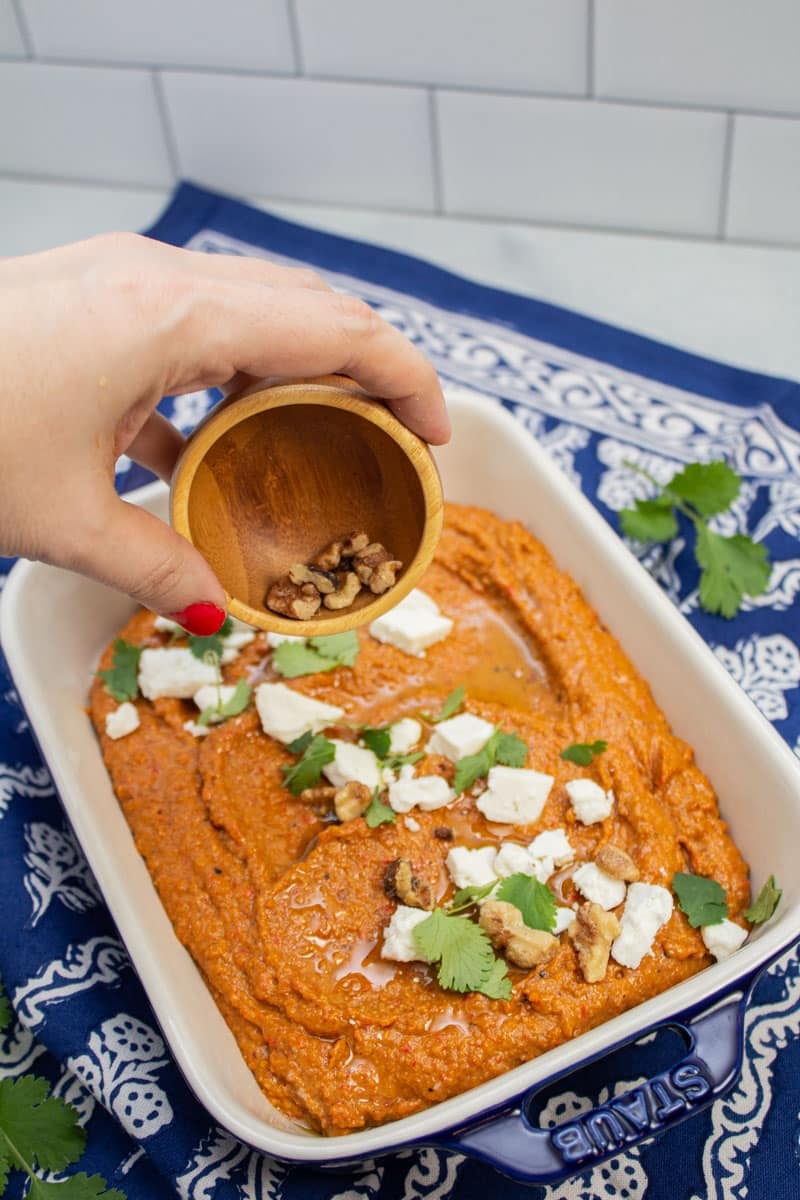 Garnishing muhammara with chopped walnuts.