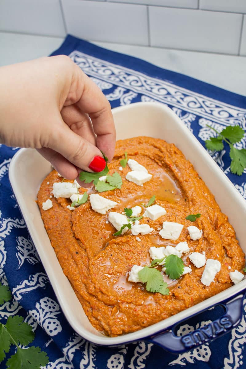 Garnishing muhammara with cilantro leaves.