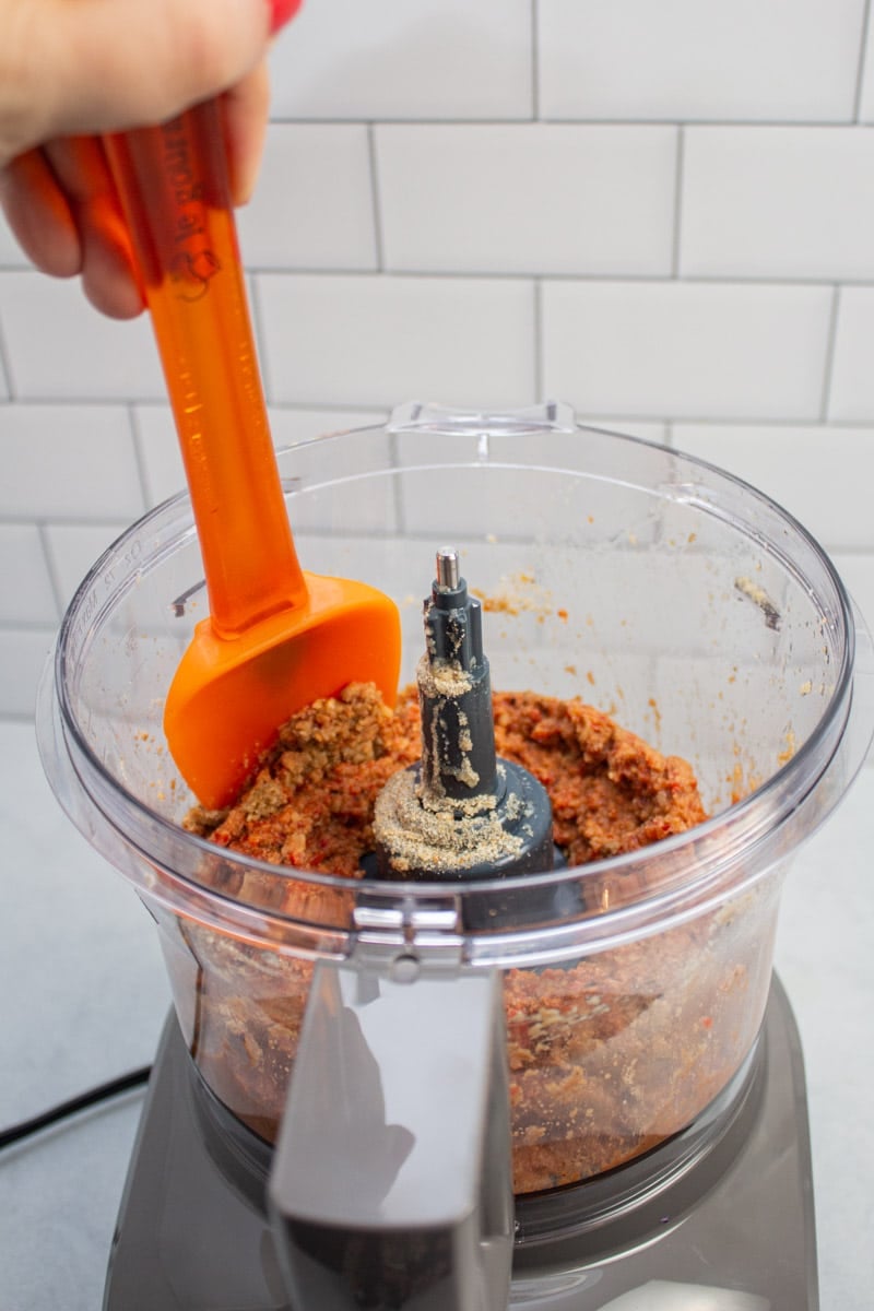 Scraping down the edges of a food processor bowl full of muhammara.