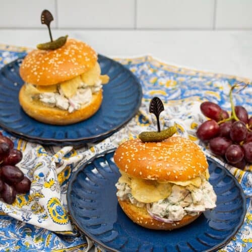 Dill chicken salad sandwiches with potato chips on plates.