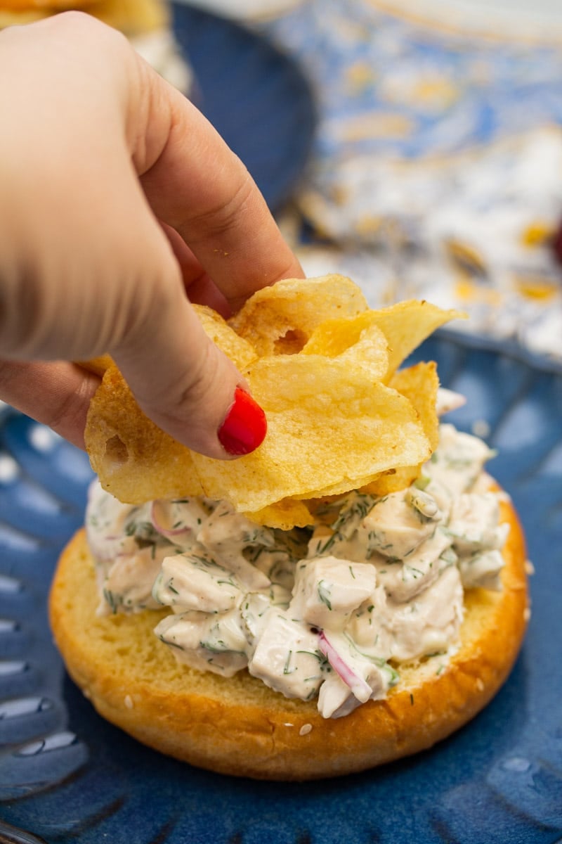 Adding potato chips to a dill chicken salad sandwich.